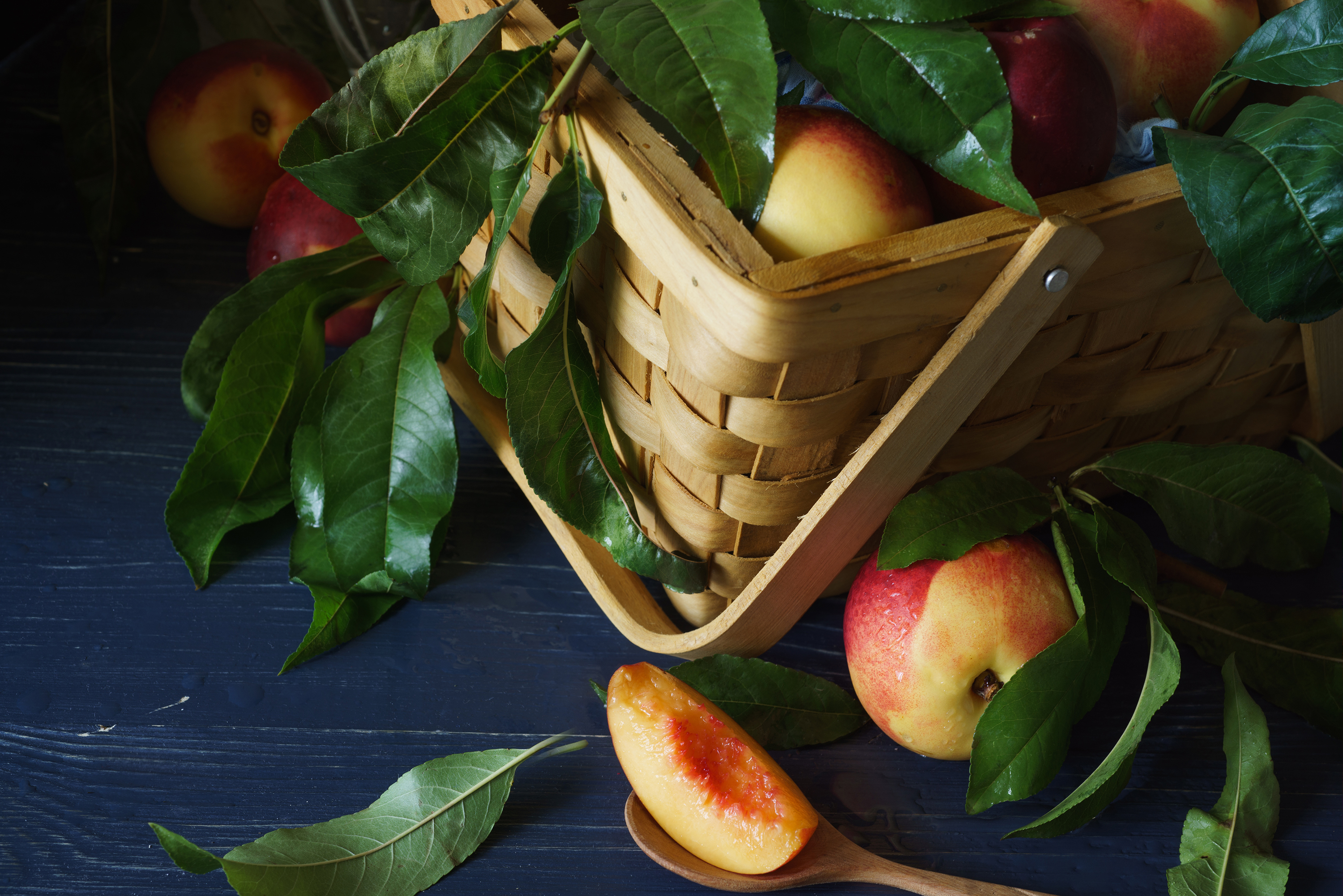 Basket of peaches on a dark wooden surface